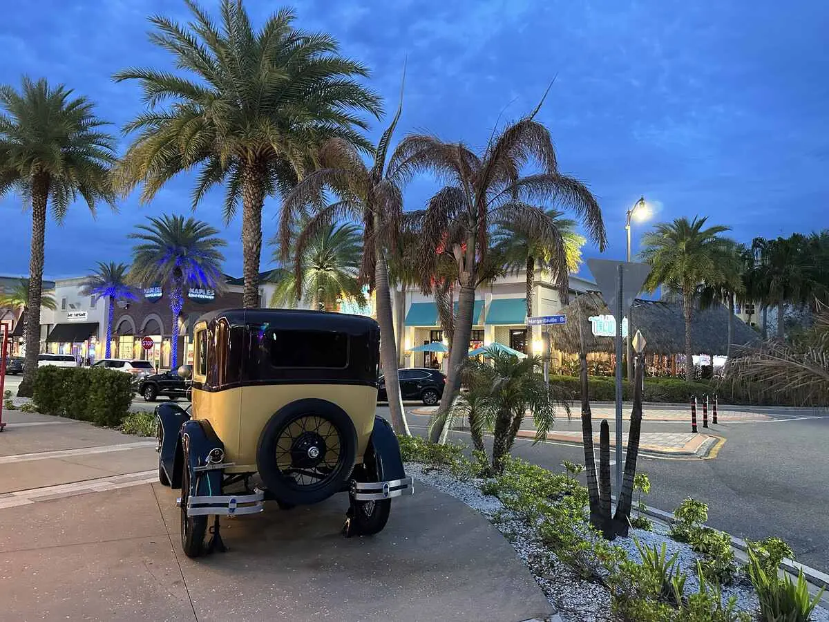 Vintage car parked near palm trees and illuminated shops at Margaritaville Resort Orlando in the evening. (Photo: Helen Hatzis/Trip Jaunt)