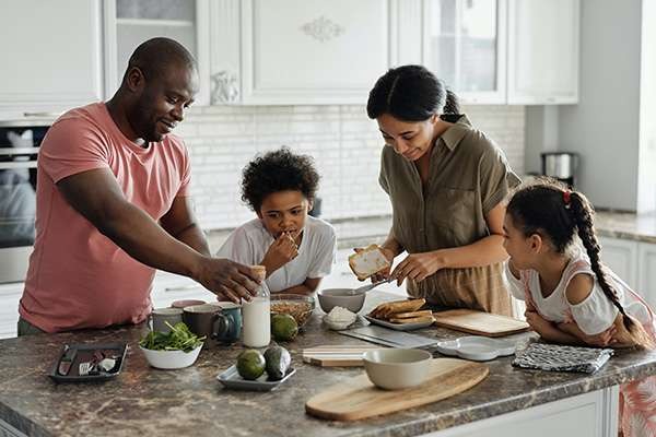 Family gathered together around a kitchen counter preparing food